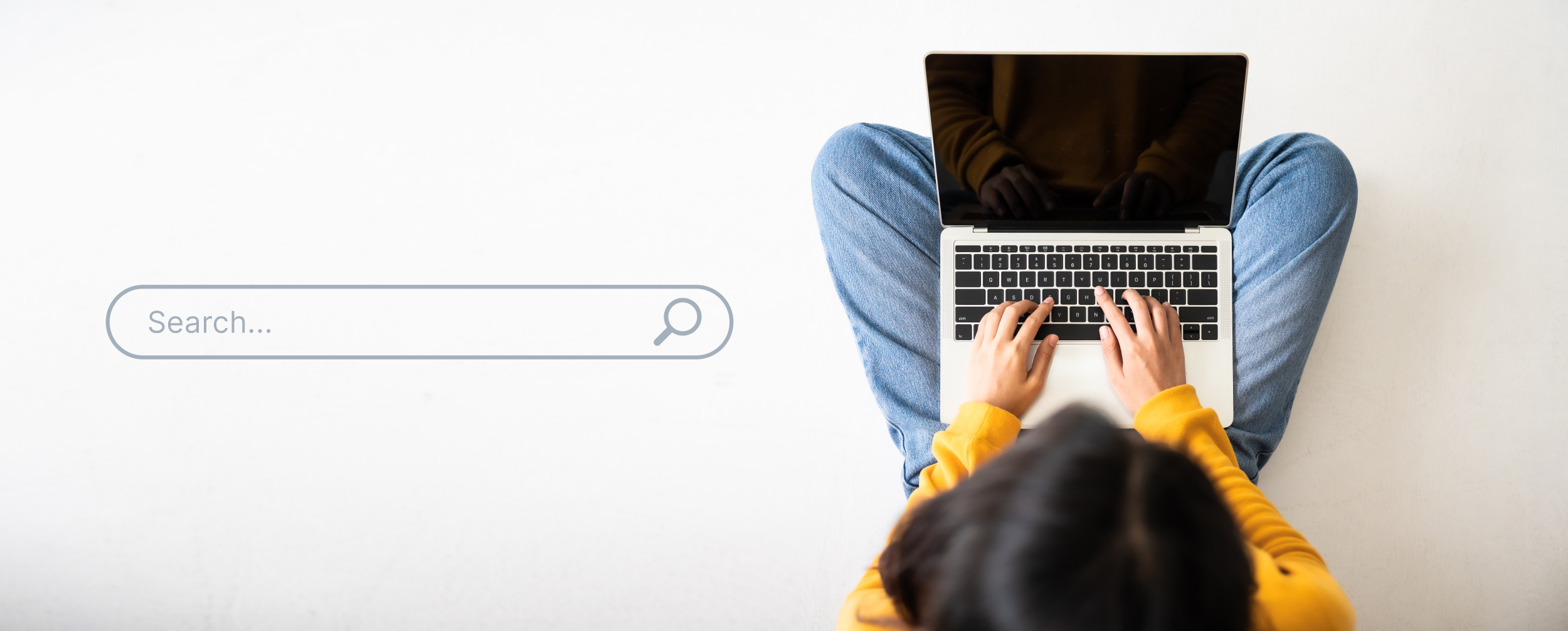 Person using a laptop with a search bar overlay on a light background